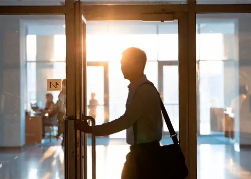 Мужчина с сумкой через плечо входит через стеклянные двери